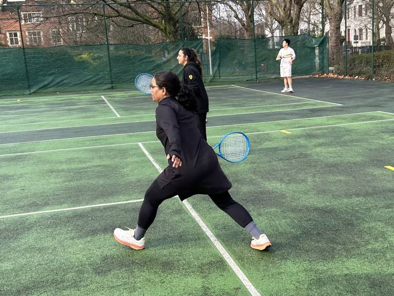 A woman lunges forward to take a shot during a community tennis lesson