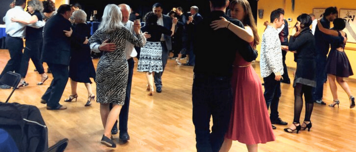 A group of people learning to dance tango in pairs