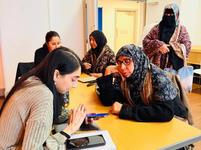 A group of women at Bernie Cameron Centre being shown by a Well One team member how to set up the NHS App on her phone.